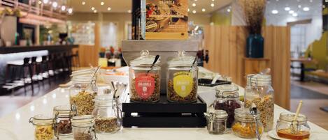 A breakfast buffet with various food items and a sign for 'Plant Granola'.