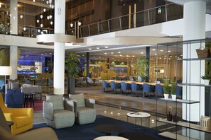 Un moderno vestíbulo de hotel con zonas de estar, un bar y un comedor.