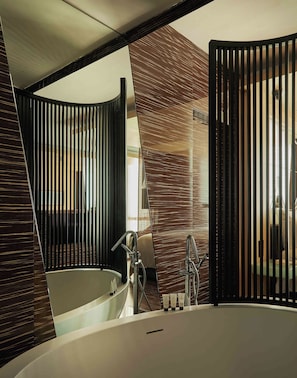 A modern bathroom with a large bathtub, a mirror, and a shower area.