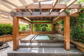 A wooden pergola structure with a hot tub underneath.