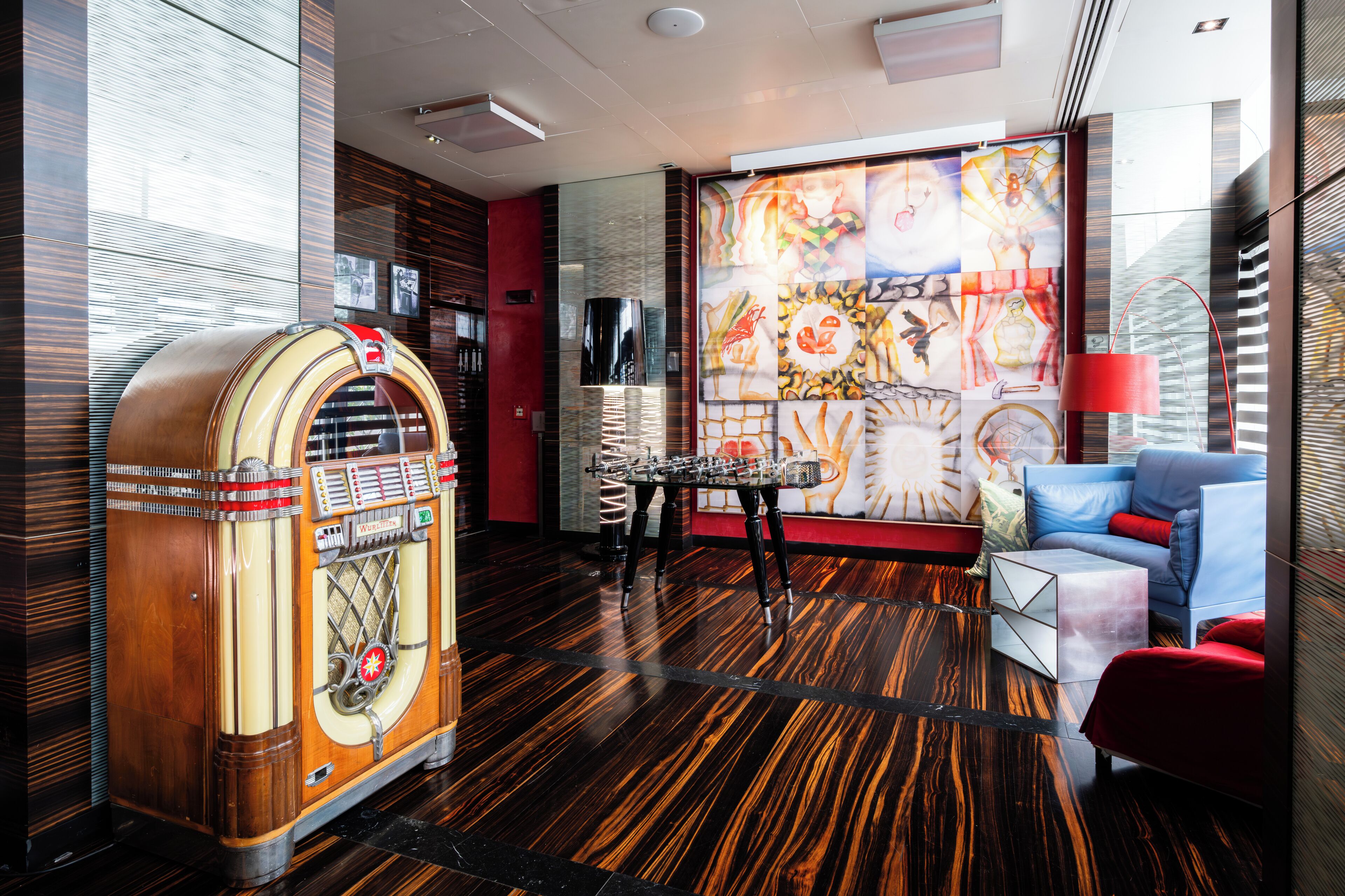 Una habitación de estilo retro con jukebox, muebles modernos y un mural colorido.
