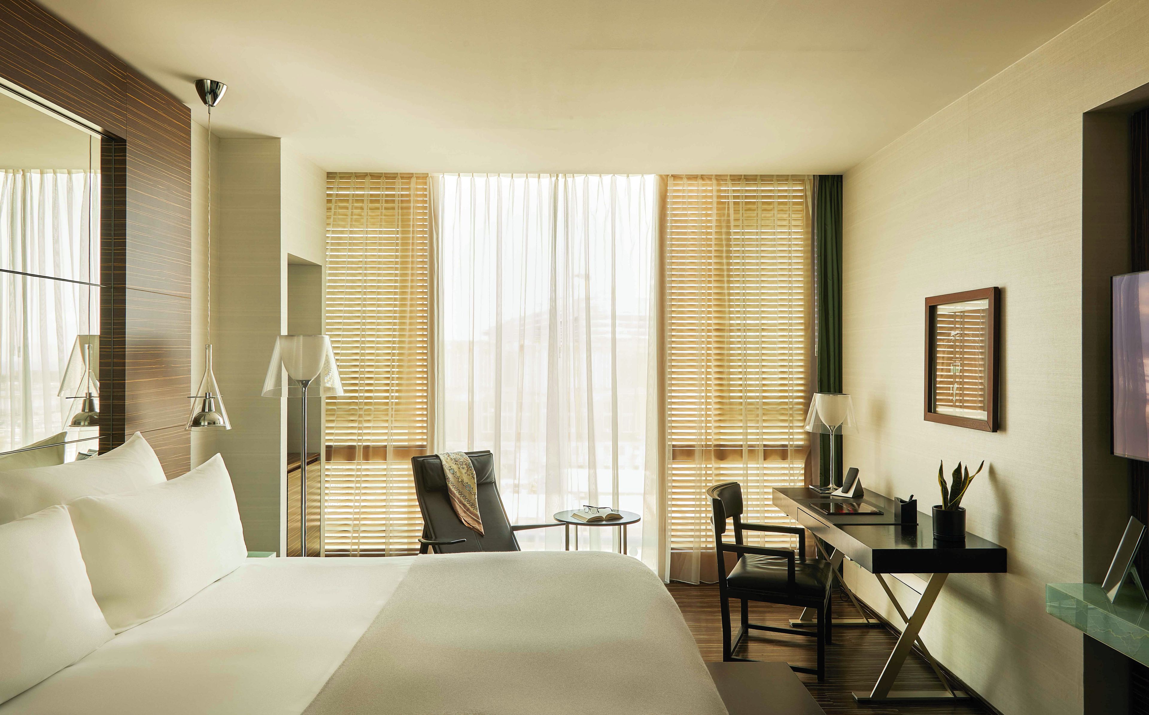 Une chambre d’hôtel équipée d’un lit, d’un bureau, d’une chaise, d’une petite table et d’un téléviseur.