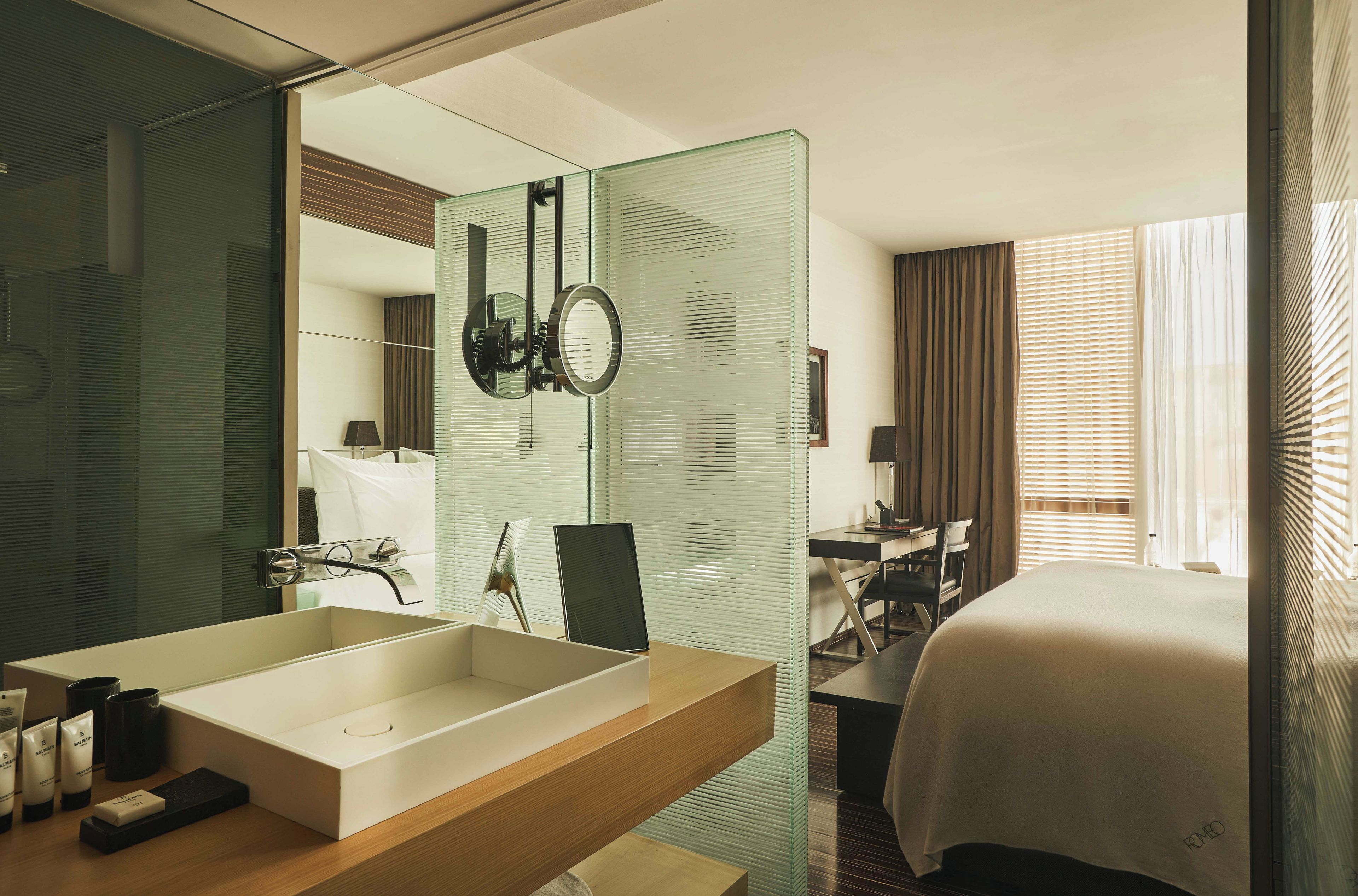 A hotel bathroom with a large mirror, a sink, and a shower area.