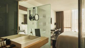 A hotel bathroom with a large mirror, a sink, and a shower area.