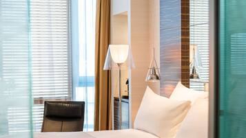 Una habitación de hotel con una cama, una silla, una lámpara y una ventana con persianas.