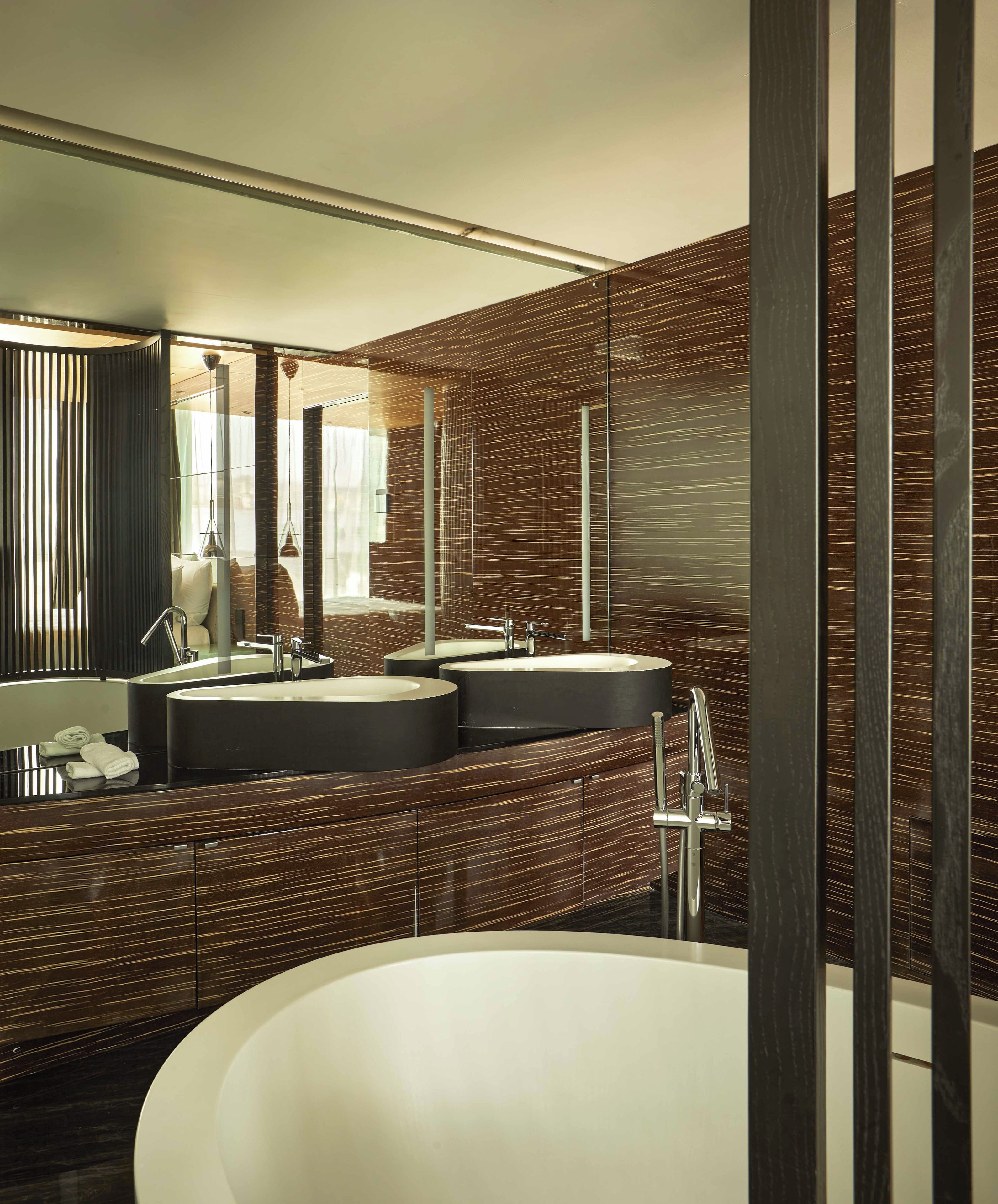 A modern bathroom with a freestanding bathtub, two sinks, and a large mirror.