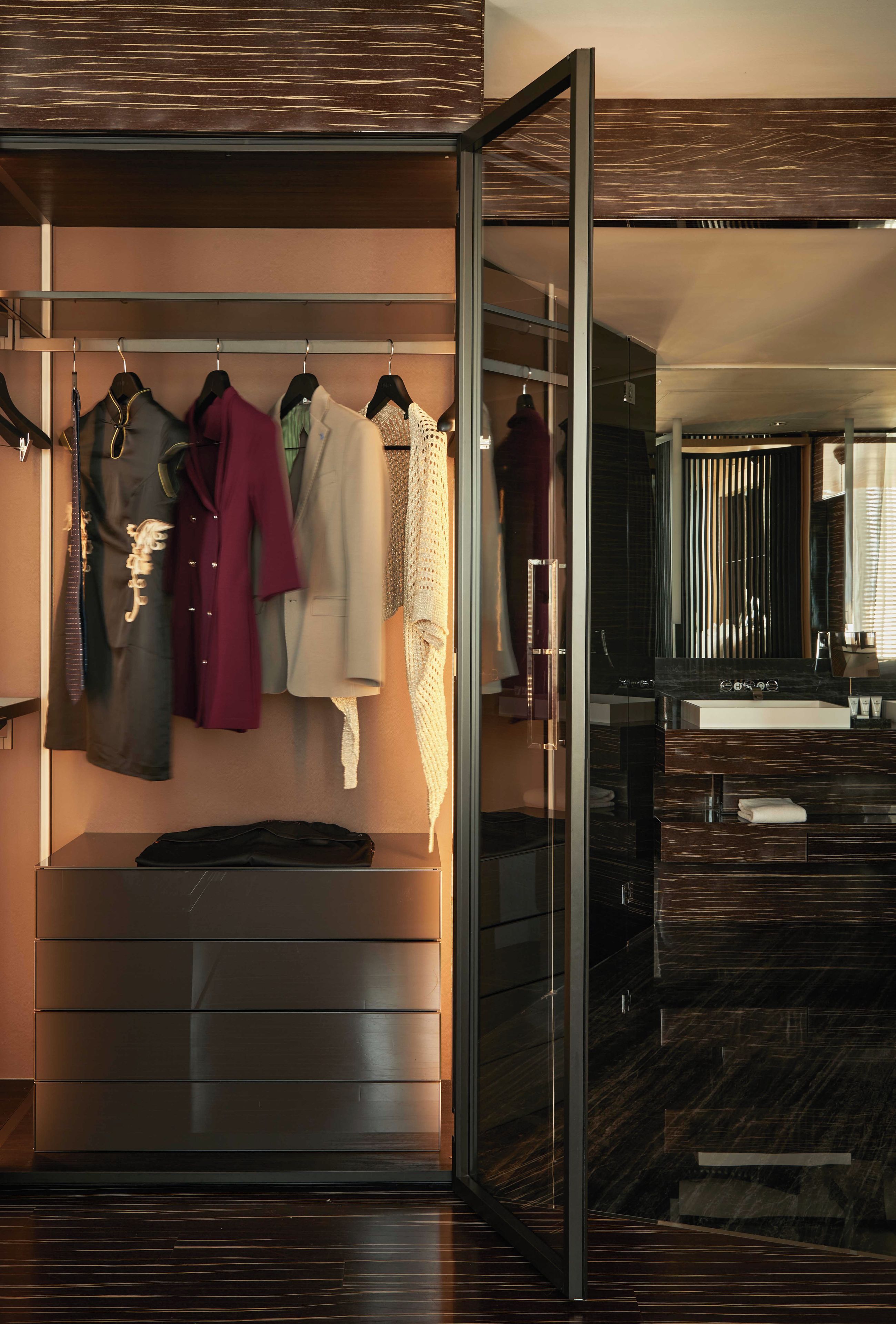 Une chambre d’hôtel moderne dotée d’un dressing où les vêtements sont rangés avec soin sur des cintres.