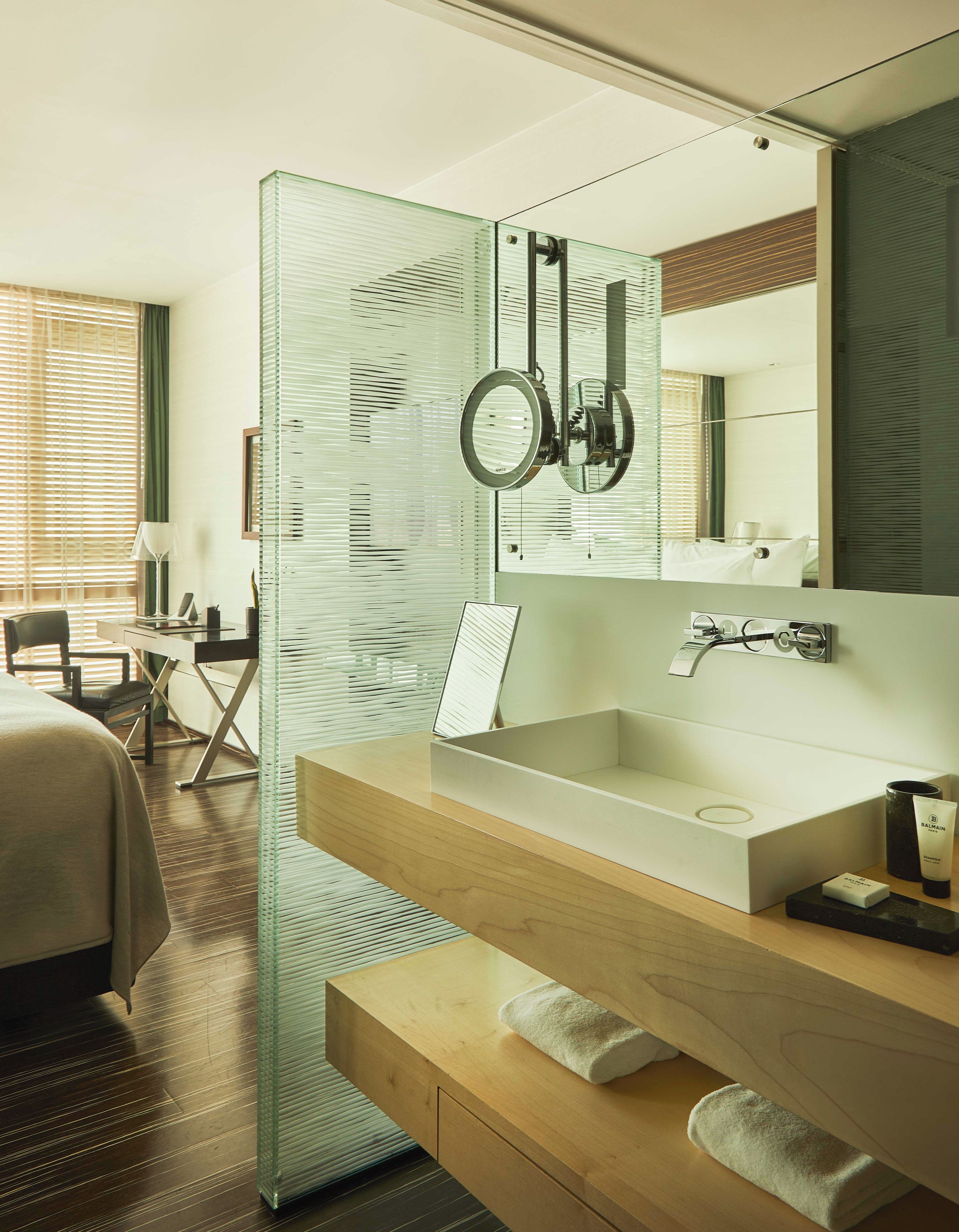 A modern bathroom with a glass partition, a large mirror, a wooden vanity, and a shower area.