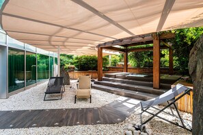 A covered outdoor area with a wooden pergola, seating, and a view of greenery. - ROMEO Napoli (Naples)