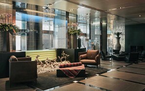 A modern lobby with a seating area, a fireplace, and a large window offering a view of the cityscape. - ROMEO Napoli (Naples)