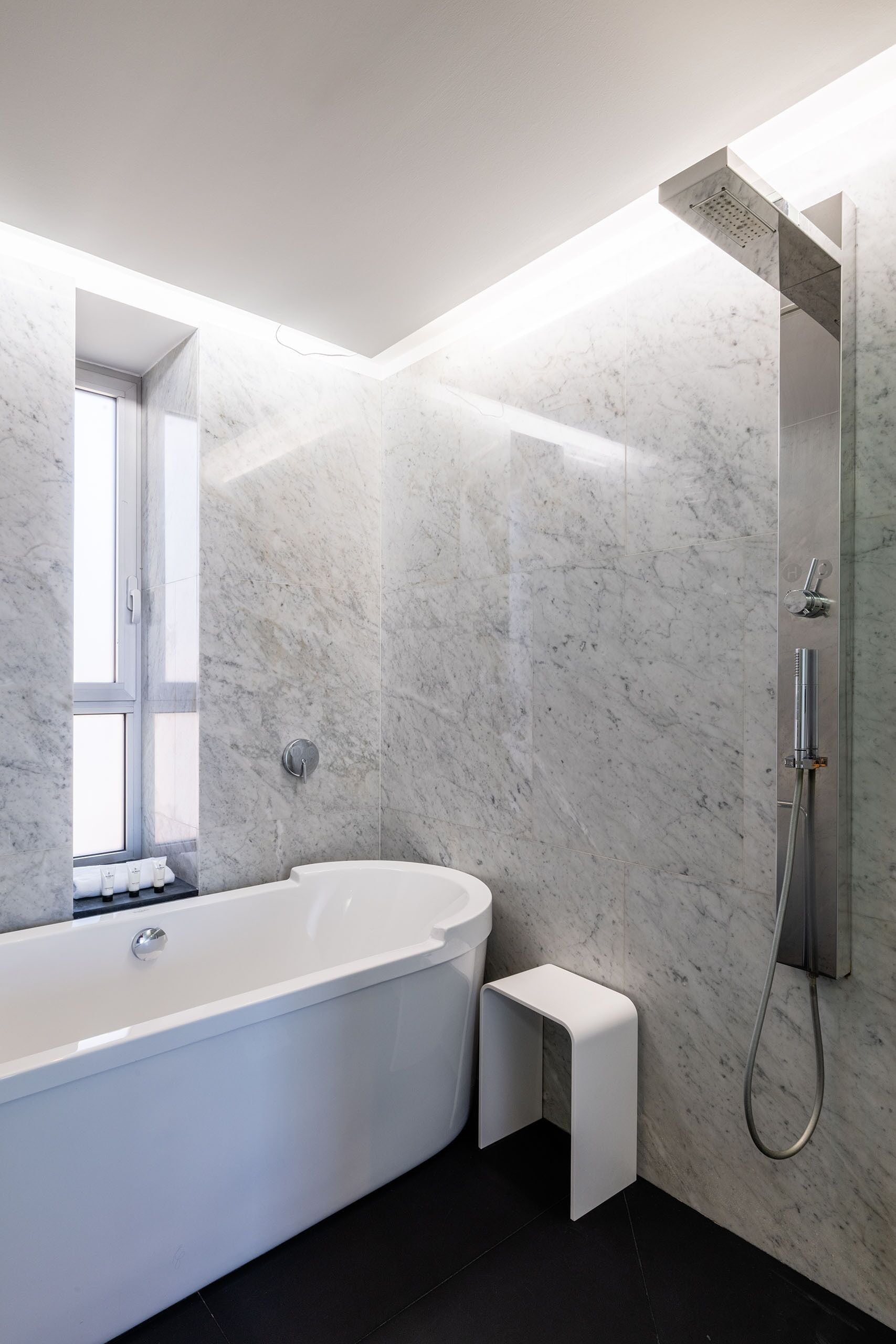 Ein modernes Badezimmer mit einer freistehenden Badewanne, einer Duschkabine und einer Marmorwand.