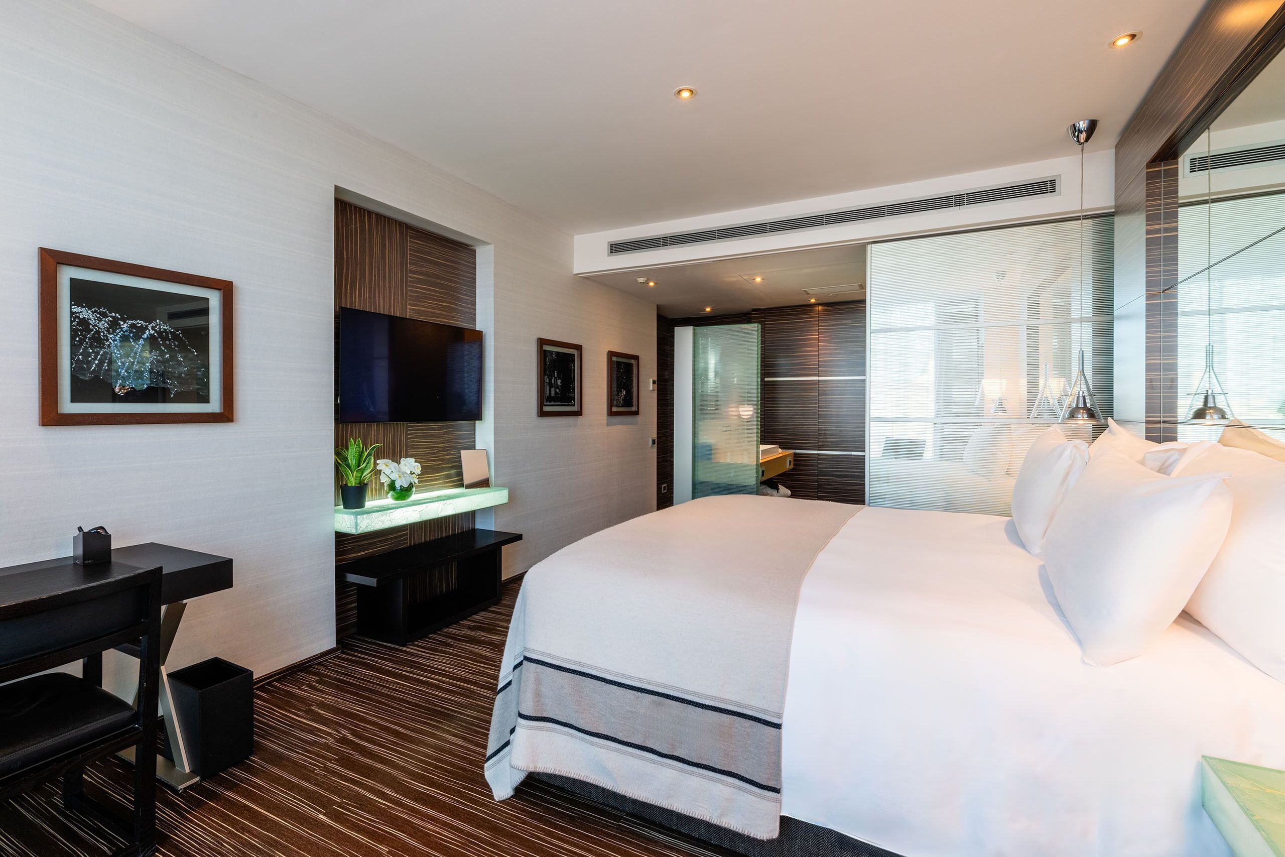 A modern hotel room with a large bed, a desk, and a seating area.