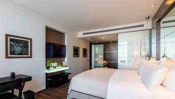 A modern hotel room with a large bed, a desk, and a seating area.