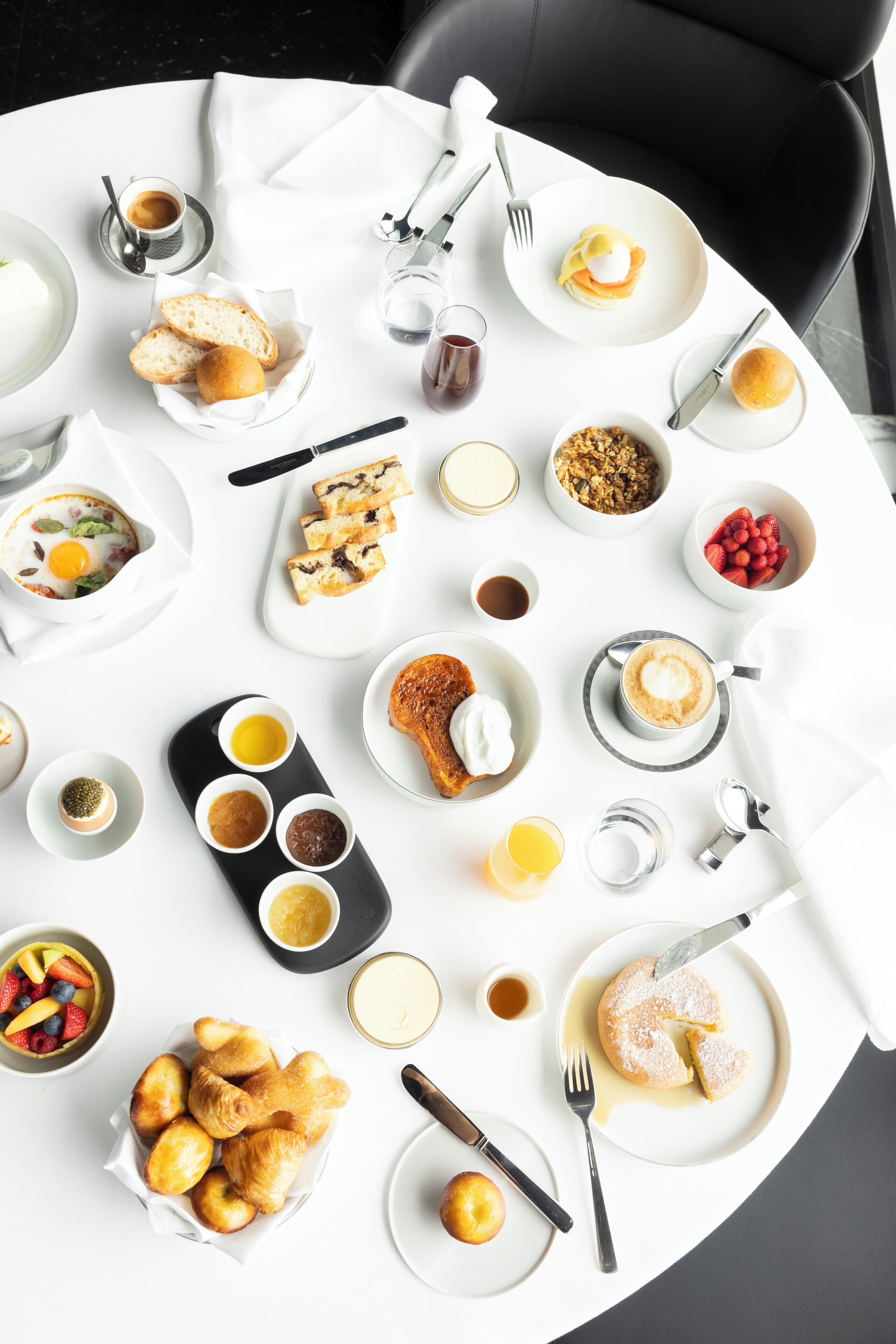 A breakfast table with various food items and utensils.