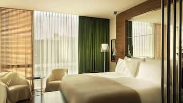 A hotel room with a bed, a chair, a small table, and a large mirror.
