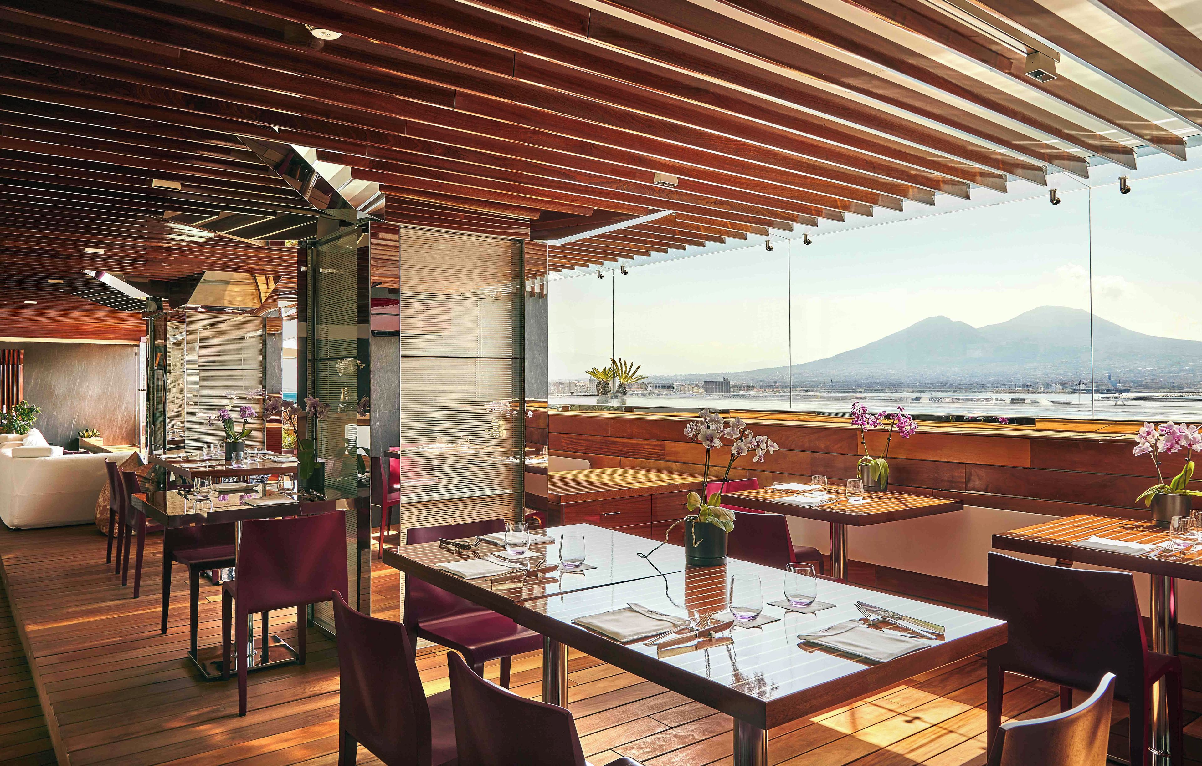 Un restaurant doté d’un plancher en bois, de tables dressées pour le service et offrant une vue sur une montagne.