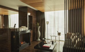 Una sala de estar moderna con chimenea, un espejo grande, una planta en maceta y vistas al exterior.