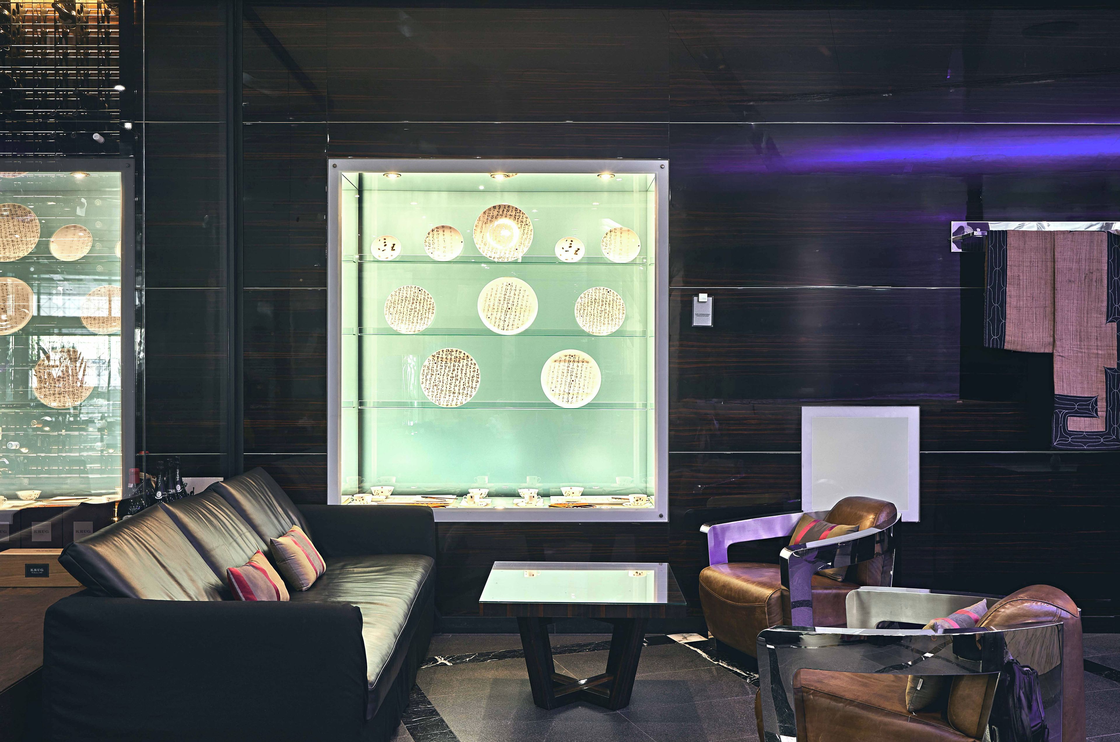 A modern interior with a seating area, a display of plates, and a wall-mounted light fixture.