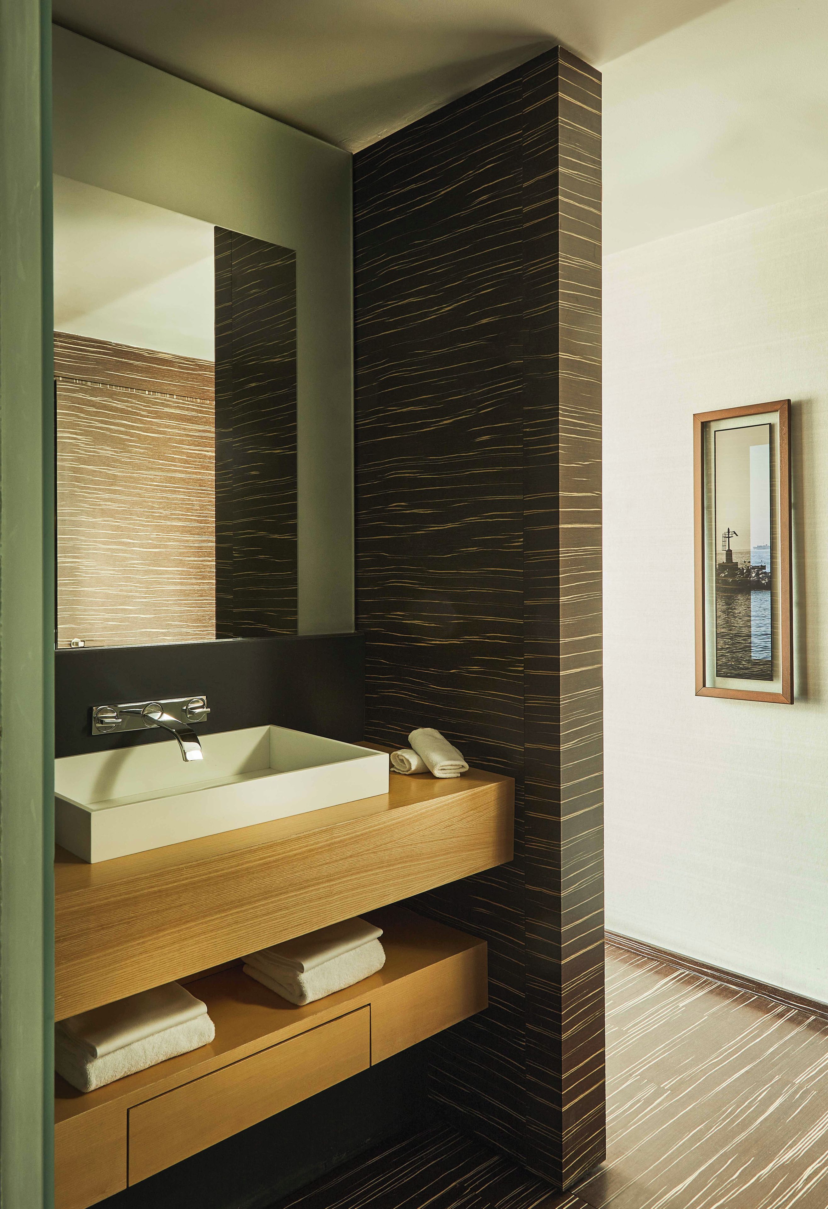 Un baño moderno con un espejo grande, un lavamanos blanco y un mueble de tocador de madera.