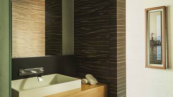 A modern bathroom with a large mirror, a white sink, and a wooden vanity.