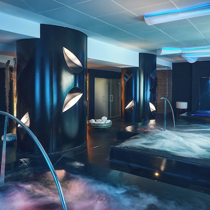 A modern spa area with a heated floor, a sauna, and a massage table.