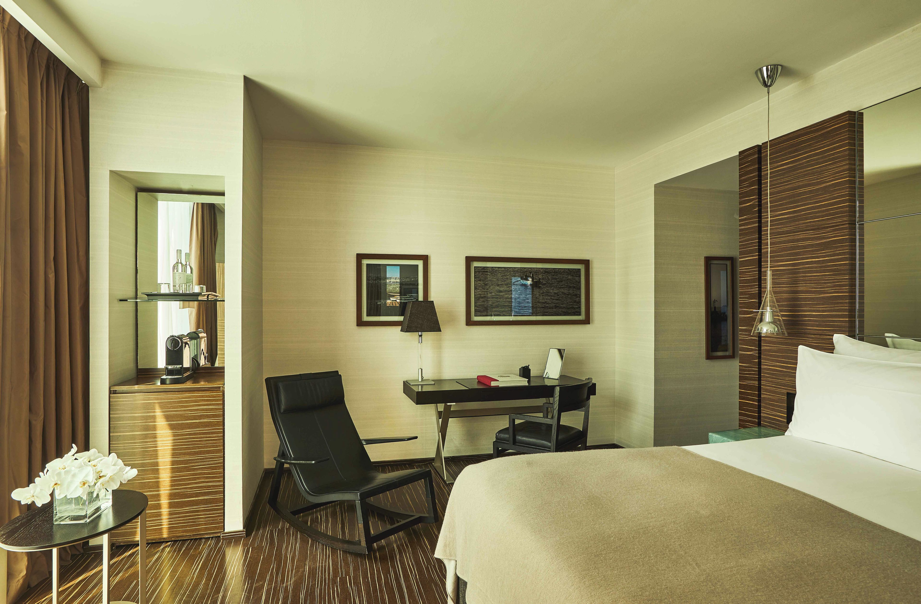 Ein Hotelzimmer mit Bett, Schreibtisch, Stuhl und einem großen Spiegel.