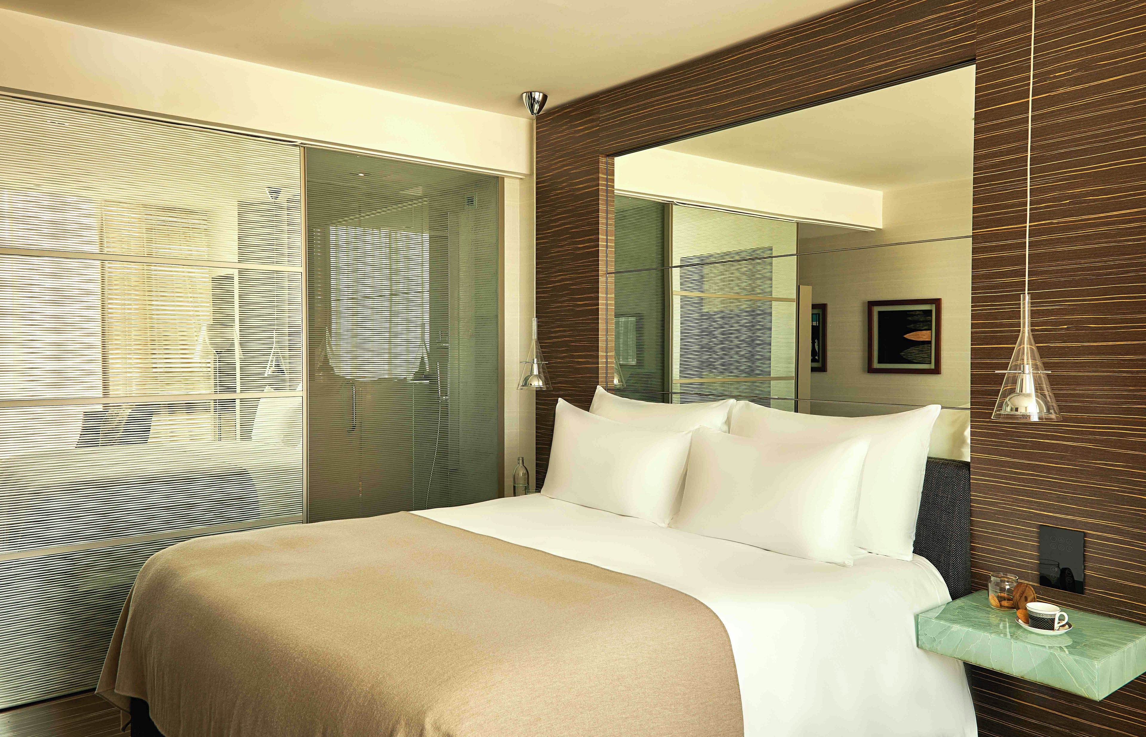 Une chambre d’hôtel avec un grand lit, une table de chevet, un miroir et une vue par la fenêtre.