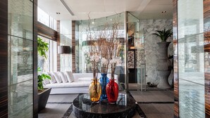 A modern lobby with a glass partition, a white sofa, and three vases with branches.