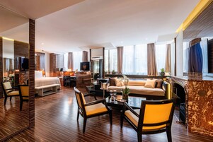Een moderne hotelkamer met een groot bed, een bank, een eethoek met stoelen, een televisie en een open haard.