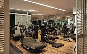 A modern gym with various exercise equipment, including treadmills and weight machines, and a wooden floor. - ROMEO Napoli (Naples)