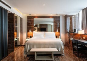 Ein modernes Hotelzimmer mit einem großen Bett, Nachttischen, einem Schreibtisch und einer Bank.