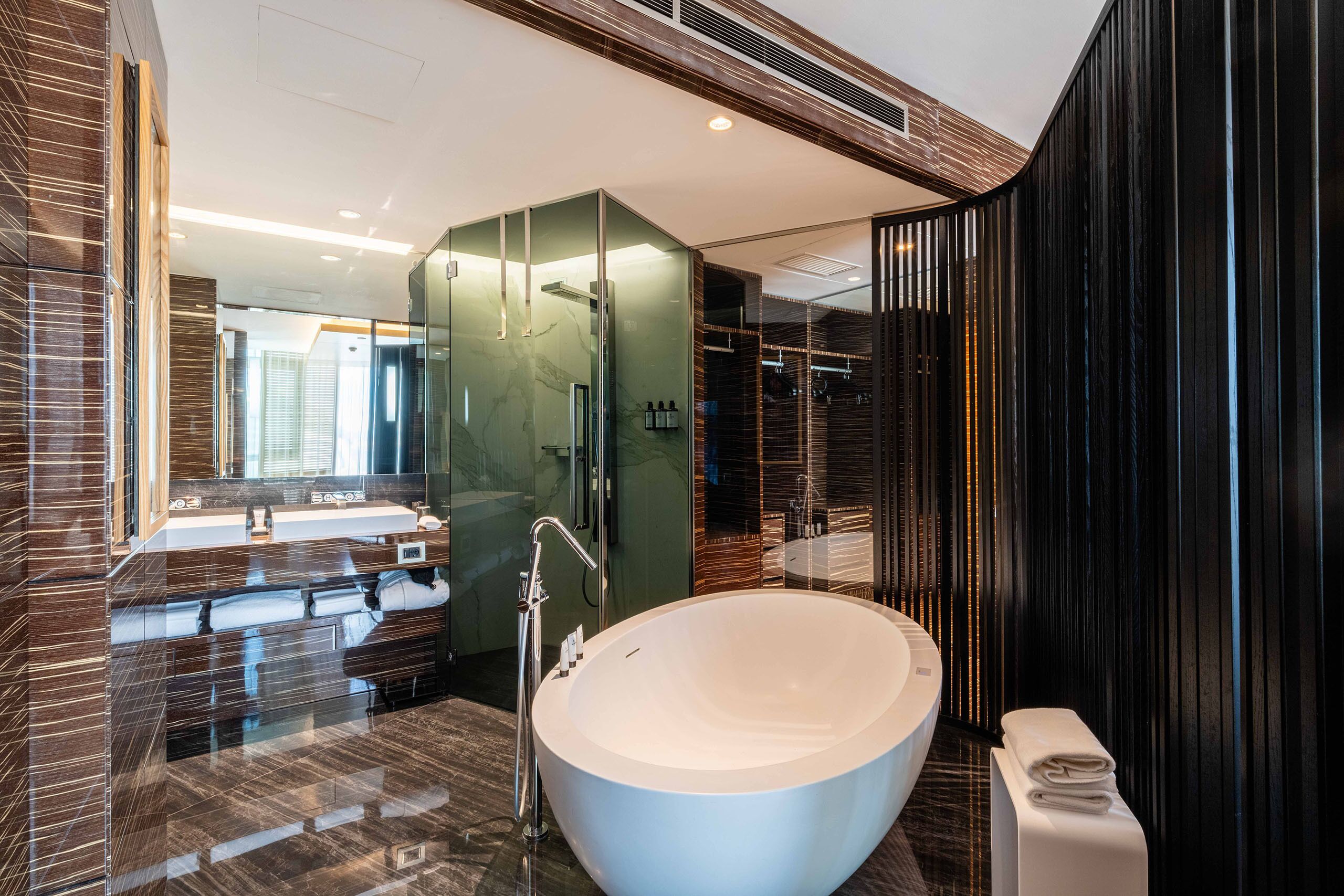 A modern bathroom with a large freestanding bathtub, a glass-enclosed shower, and a vanity with a mirror.