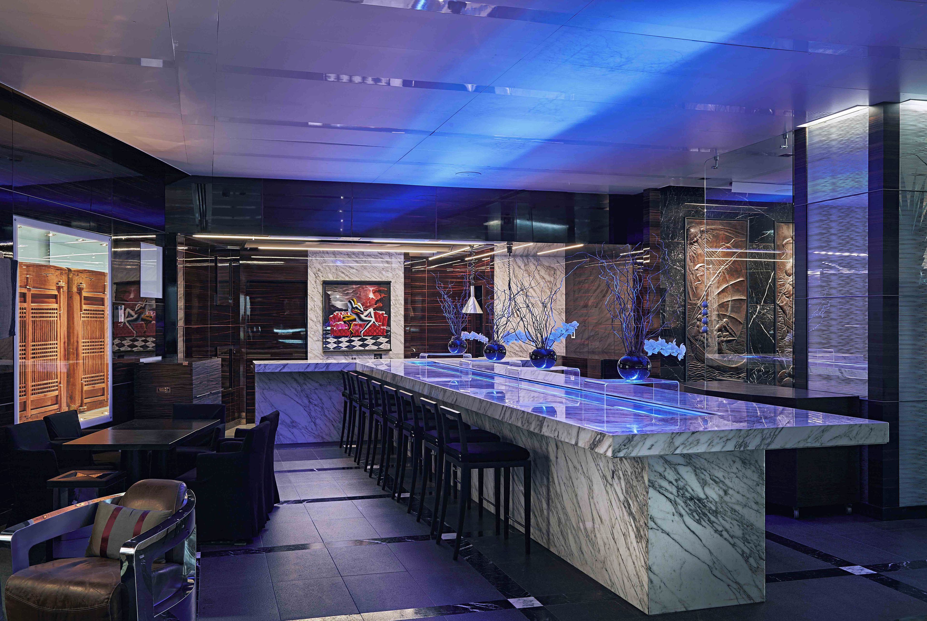 A modern bar area with a marble countertop, bar stools, and a decorative centerpiece.