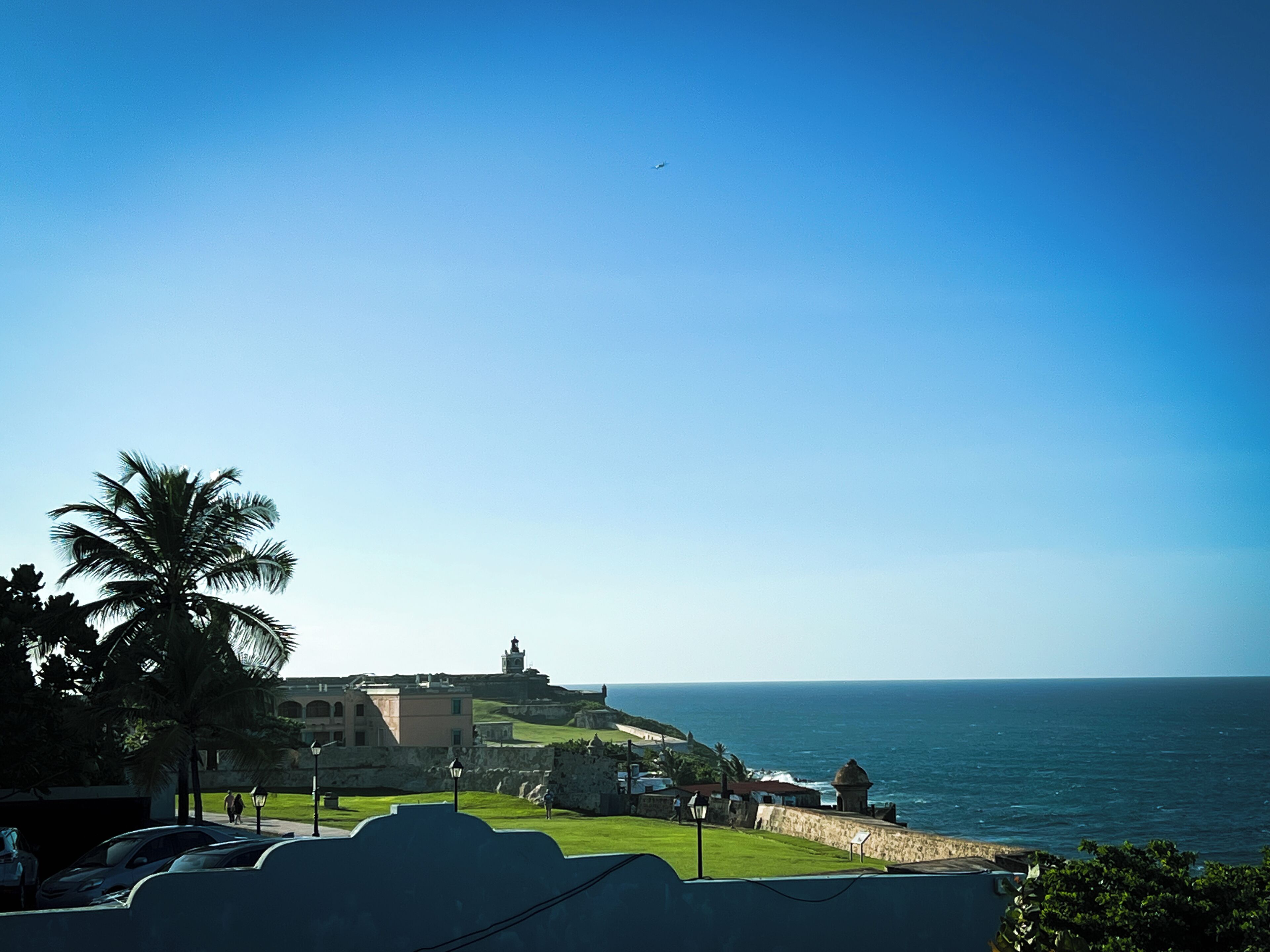 A coastal fort with a lighthouse, palm trees, and a view of the ocean.