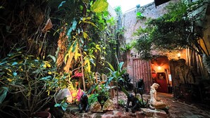 A courtyard with a stone wall, potted plants, and a statue of a man. - The Gallery Inn (San Juan)
