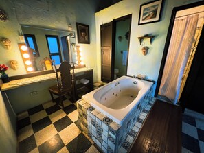 A bathroom with a checkered floor, a bathtub, a vanity with a mirror, and a shower area.