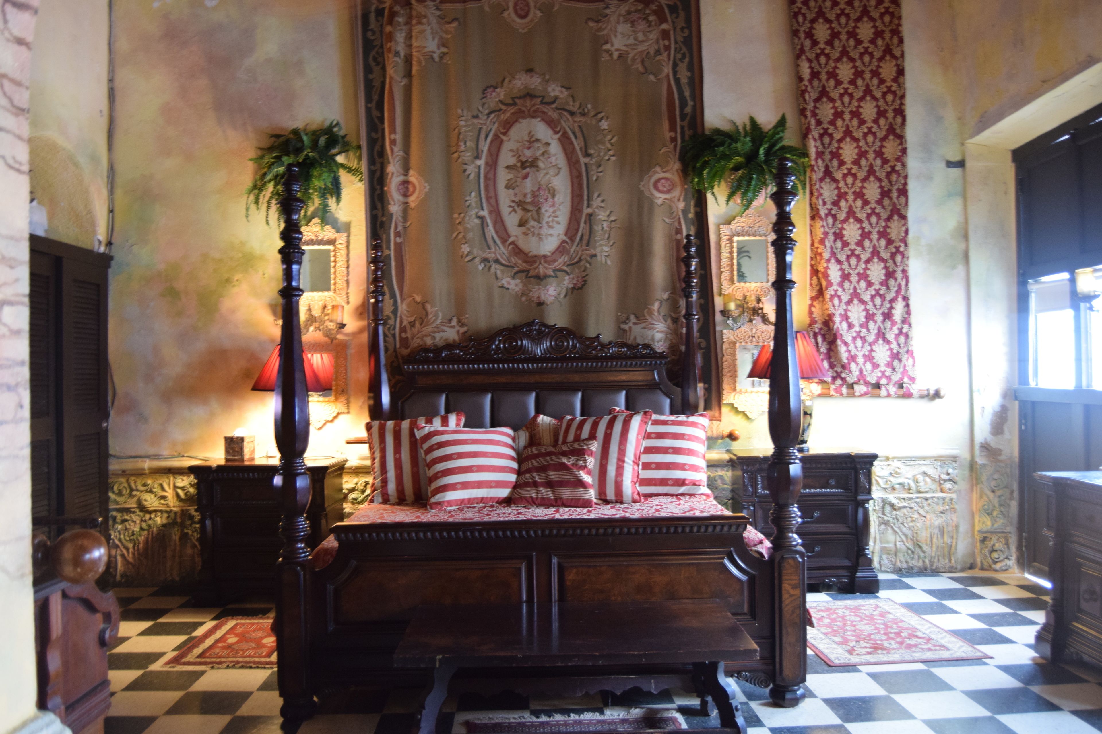 Une chambre à coucher de style traditionnel, avec un grand lit, une tête de lit décorée et deux tables de chevet avec des lampes.