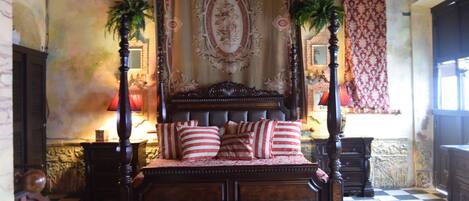 Une chambre à coucher de style traditionnel, avec un grand lit, une tête de lit décorée et deux tables de chevet avec des lampes.