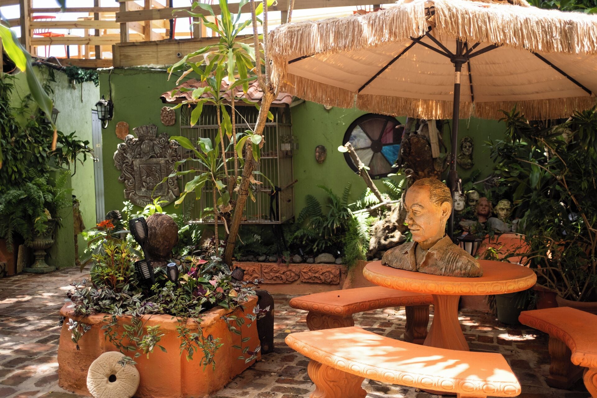 An outdoor patio with terracotta planters, a stone table, and a thatched umbrella.