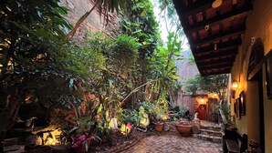 A courtyard with a cobblestone path, potted plants, and a statue. - The Gallery Inn (San Juan)