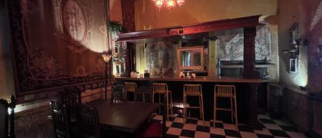A bar area with a checkered floor, bar stools, and a large mirror above the bar.