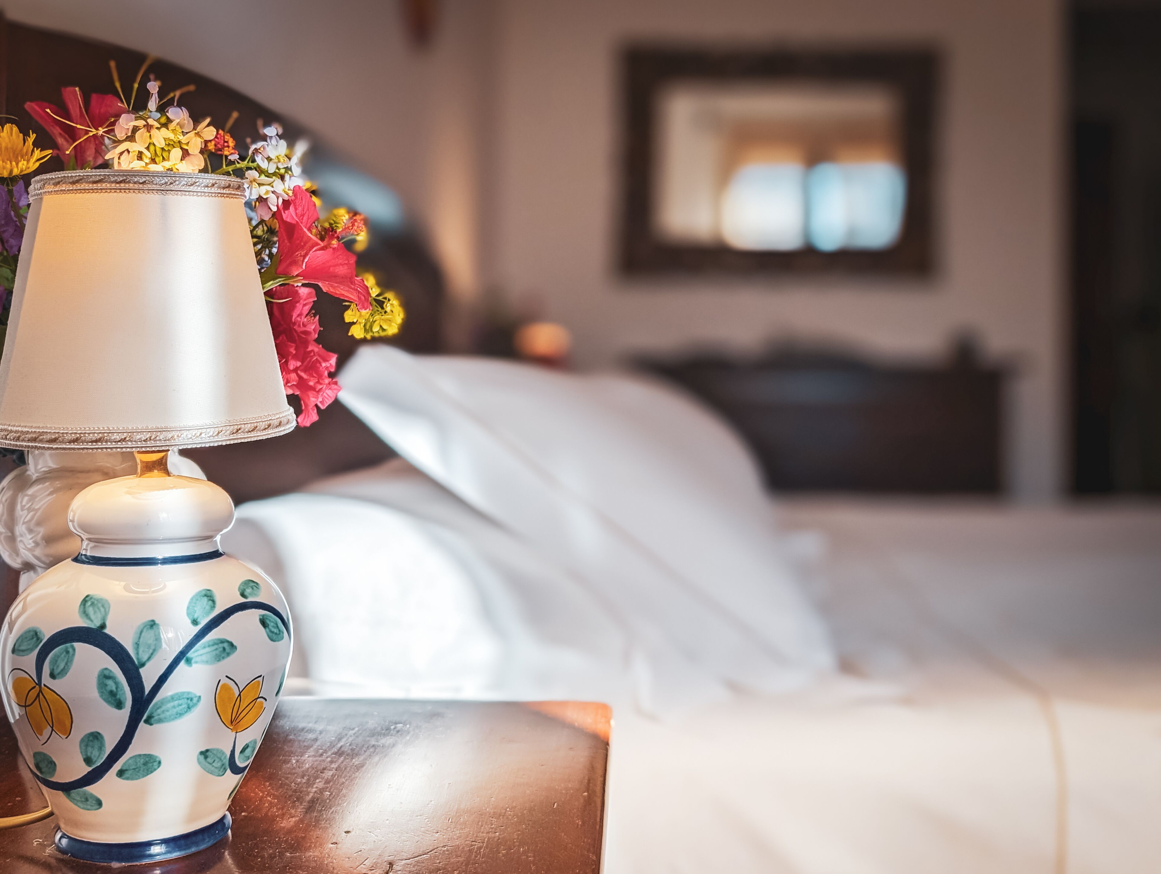 Una mesita de noche con una lámpara decorativa y un arreglo floral.