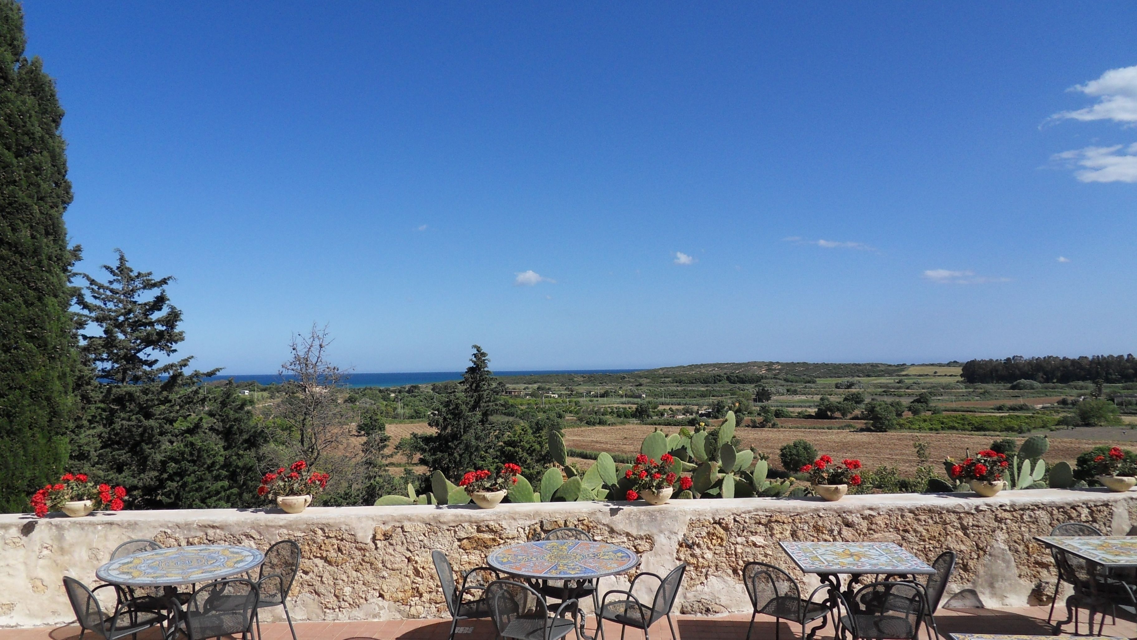 Terraço com mesas ao ar livre e vista para o mar.