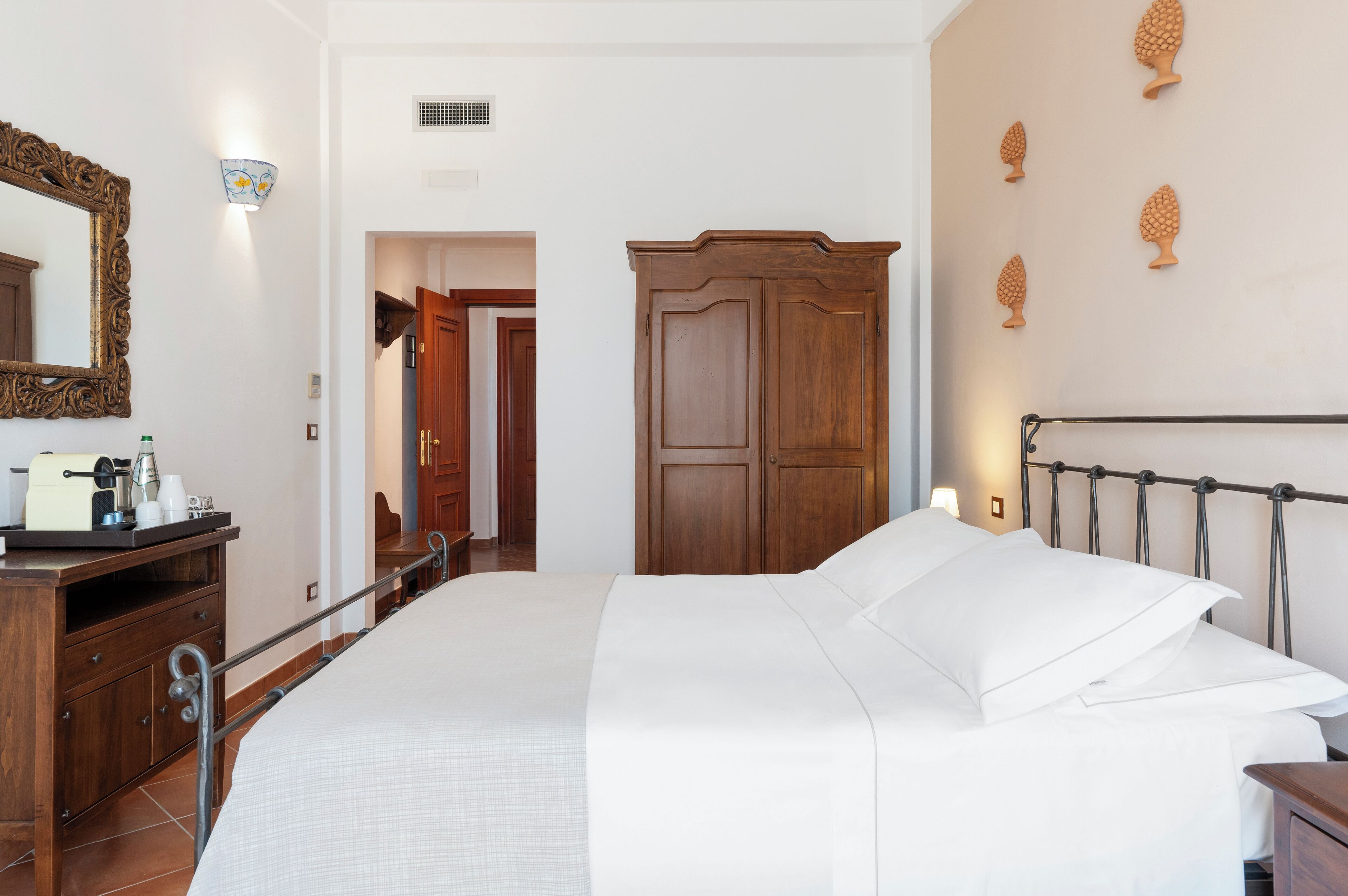 A neatly arranged bedroom with a large bed, a wooden wardrobe, a dresser, and a mirror.