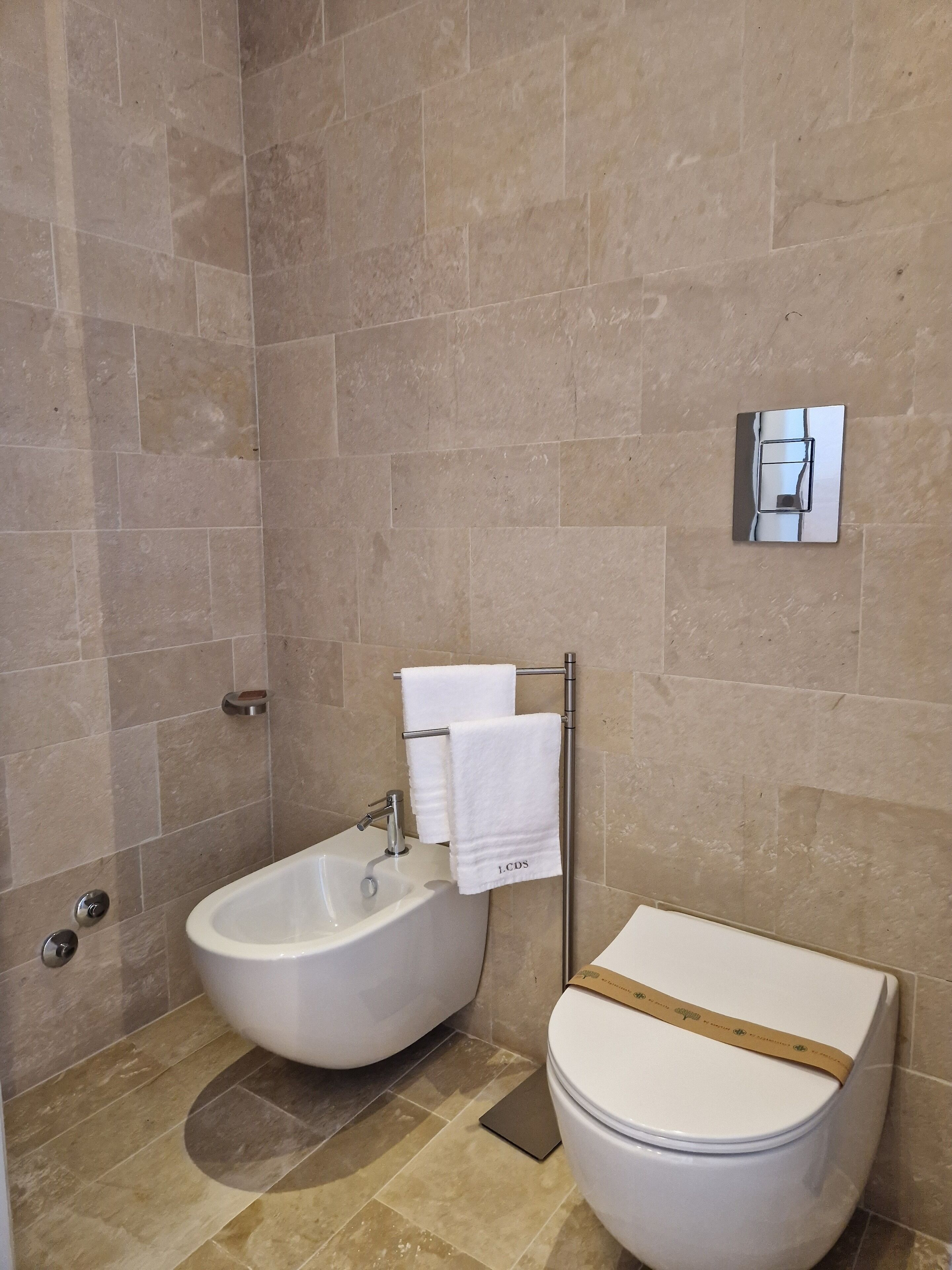Une salle de bain équipée d’un bidet, de toilettes et d’un porte-serviettes.