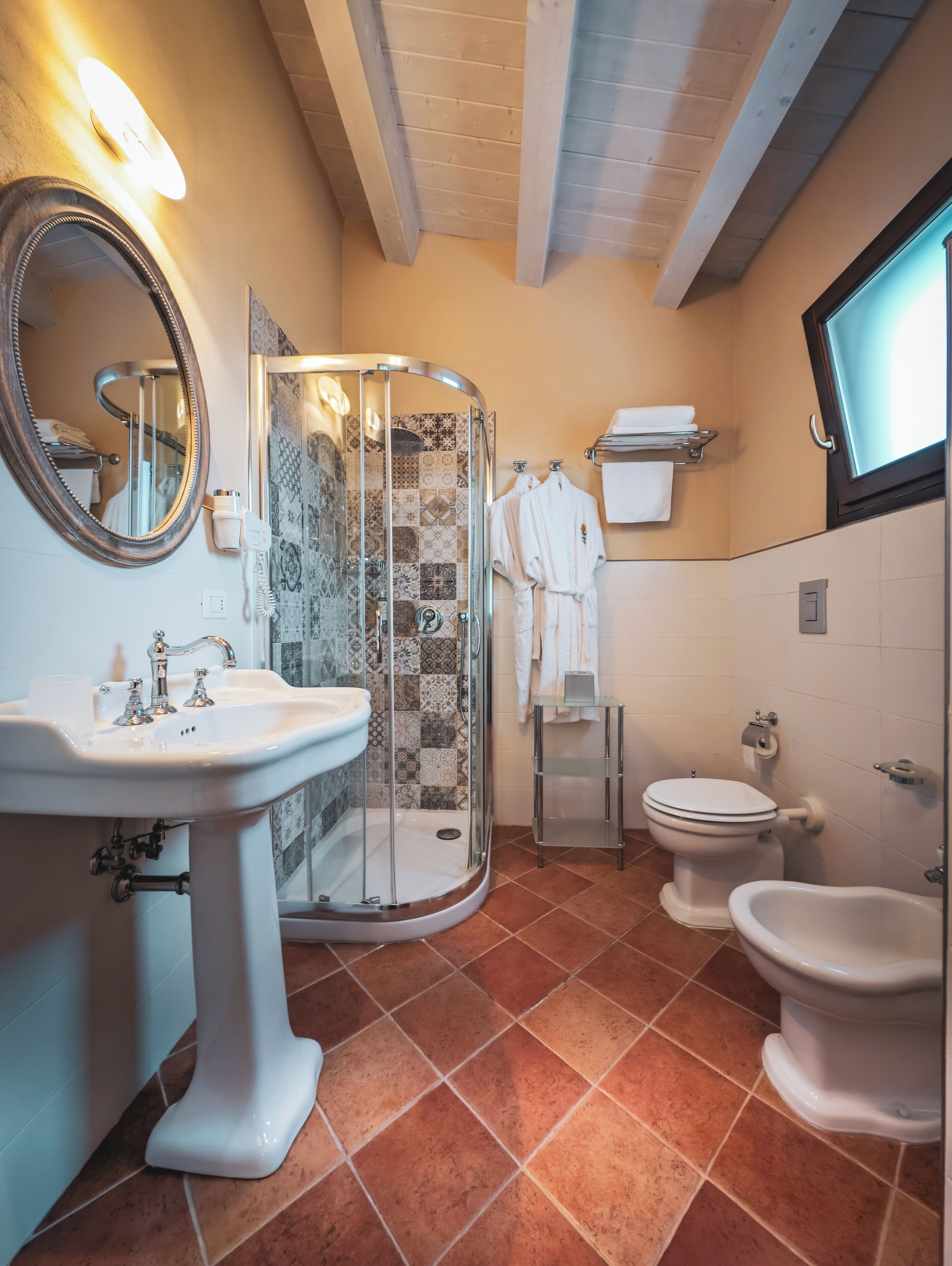 A bathroom with a shower, toilet, bidet, and sink.