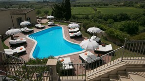 A pool area with lounge chairs and umbrellas, surrounded by a scenic landscape. - La Corte Del Sole (Noto)