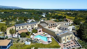 A resort with a swimming pool, outdoor seating, and a view of the surrounding landscape. - La Corte Del Sole (Noto)