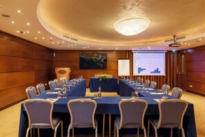 Een vergaderzaal met een lange tafel, stoelen, een projectiescherm en een presentatie.