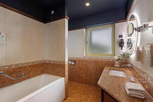 Un baño con bañera, lavamanos, espejo y ventana.